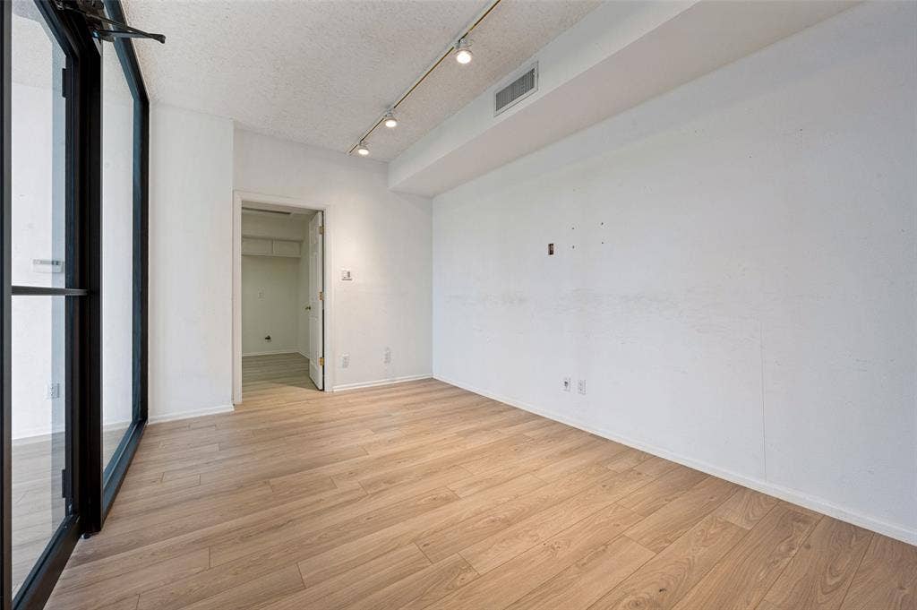 5200 Keller Springs Road, #522, Dallas, TX 75248 Wood-finish flooring, floor-to-ceiling black-framed glass paneling, and adjustable directional track lighting