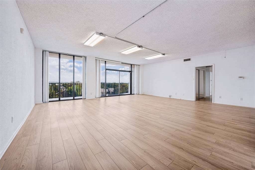 5200 Keller Springs Road, #522, Dallas, TX 75248 Spacious room featuring wood-finish flooring, floor-to-ceiling glass sliding doors, and industrial-style surface-mounted lighting