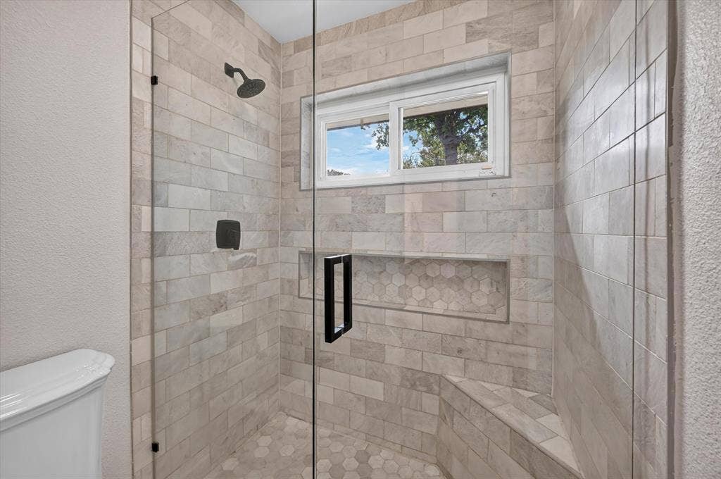Downstairs ensuite surrounds, hexagonal tile flooring, a built-in bench, recessed shower niche, and matte black hardware