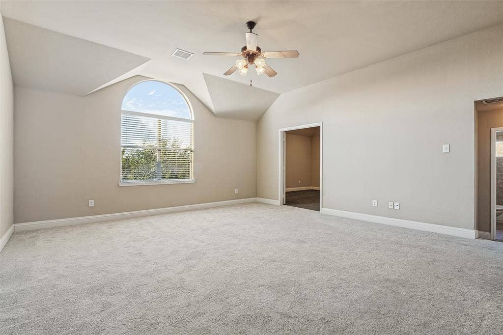 1380 Riverside Oaks Drive, Rockwall, TX 75087 Vaulted ceilings featuring an arched window, neutral wall coloring, and a central ceiling fan with integrated lighting
