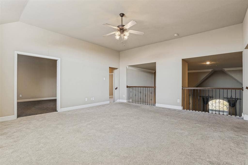 1380 Riverside Oaks Drive, Rockwall, TX 75087 Vaulted ceilings, carpeted flooring, multi-blade ceiling fan with integrated lighting, and decorative metal baluster railings