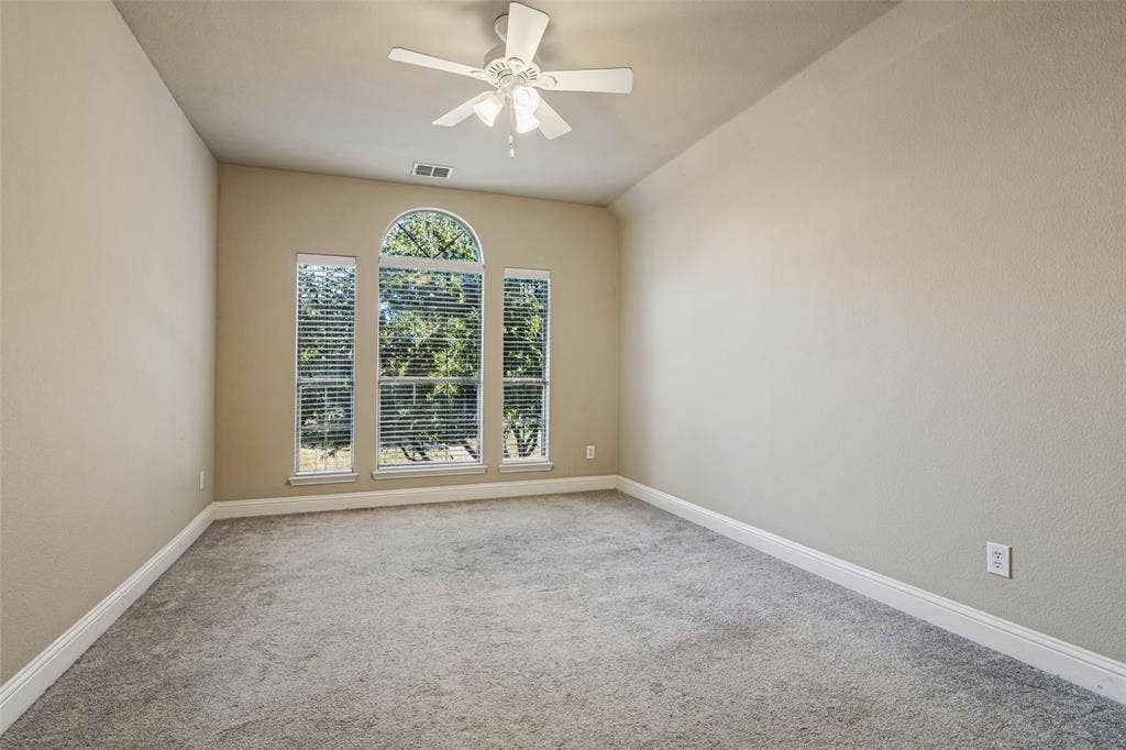 1380 Riverside Oaks Drive, Rockwall, TX 75087 Neutral-toned interior featuring carpeting, a centrally located ceiling fan with integrated lighting, and a set of windows including a central arched window