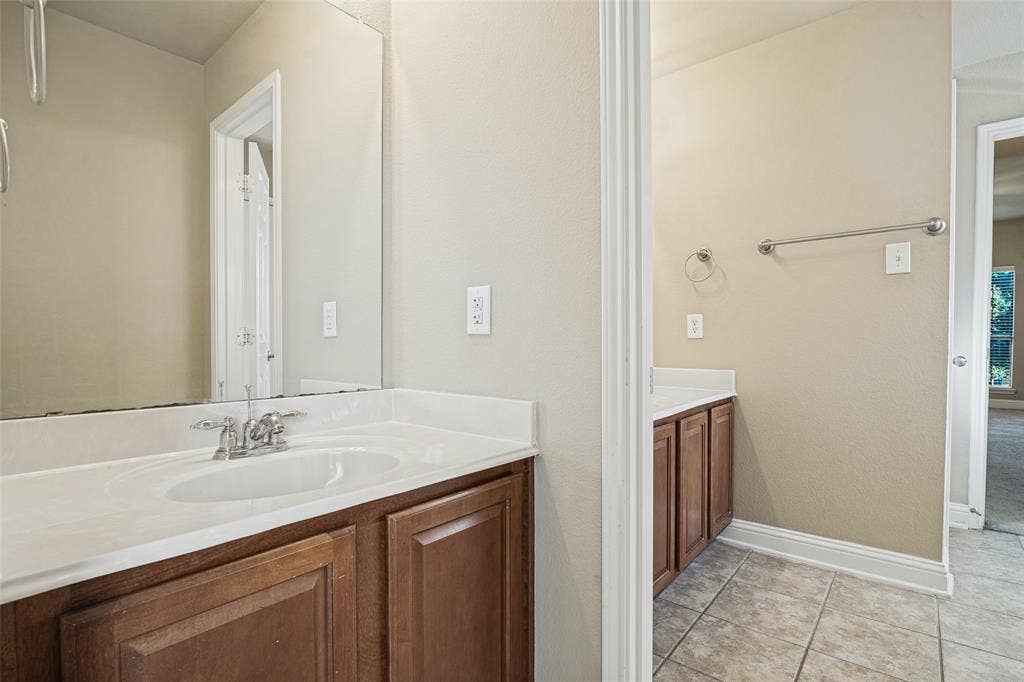 1380 Riverside Oaks Drive, Rockwall, TX 75087 Dual vanity area featuring wood-finish cabinetry, white solid-surface countertops with integrated sinks, polished chrome hardware, and large wall-mounted mirrors