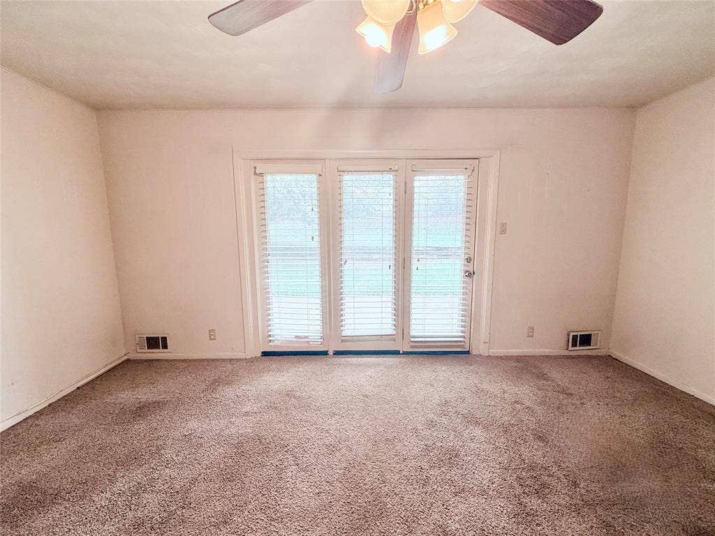 1500 S Houston, Denison, TX 75020 Triple-pane glass patio doors featuring integrated blinds, wall-to-wall carpeting, and a ceiling-mounted light fixture with a fan