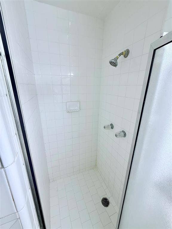 1500 S Houston, Denison, TX 75020 Shower stall featuring white square wall tile, white rectangular floor tile, integrated recessed soap niche, and metal hardware