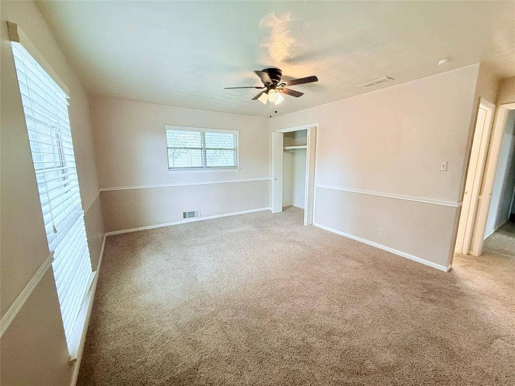 1500 S Houston, Denison, TX 75020 Room featuring neutral-toned walls with horizontal chair rail molding, wall-to-wall carpeting, ceiling fan with integrated lighting, and a closet with sliding doors