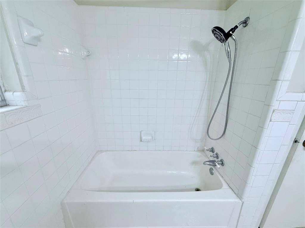1500 S Houston, Denison, TX 75020 Built-in white porcelain tub with square tile surround, chrome hand-held shower fixture, and recessed soap dish