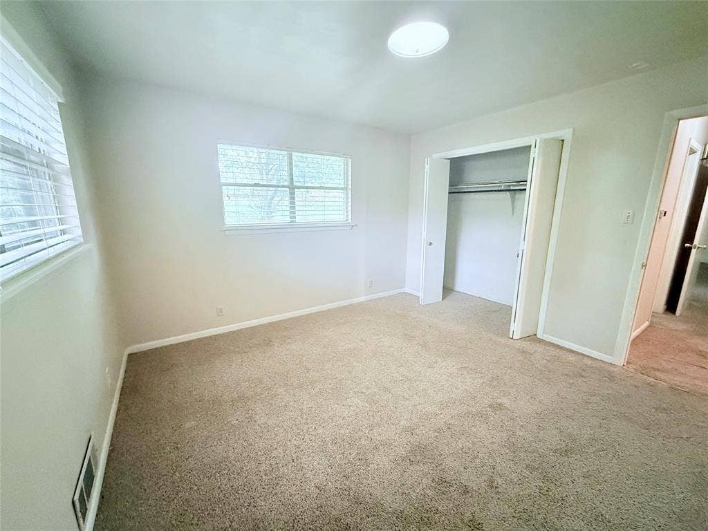 1500 S Houston, Denison, TX 75020 Neutral wall color, carpeted flooring, dual-pane windows with horizontal blinds, ceiling-mounted light fixture, and closet with sliding doors