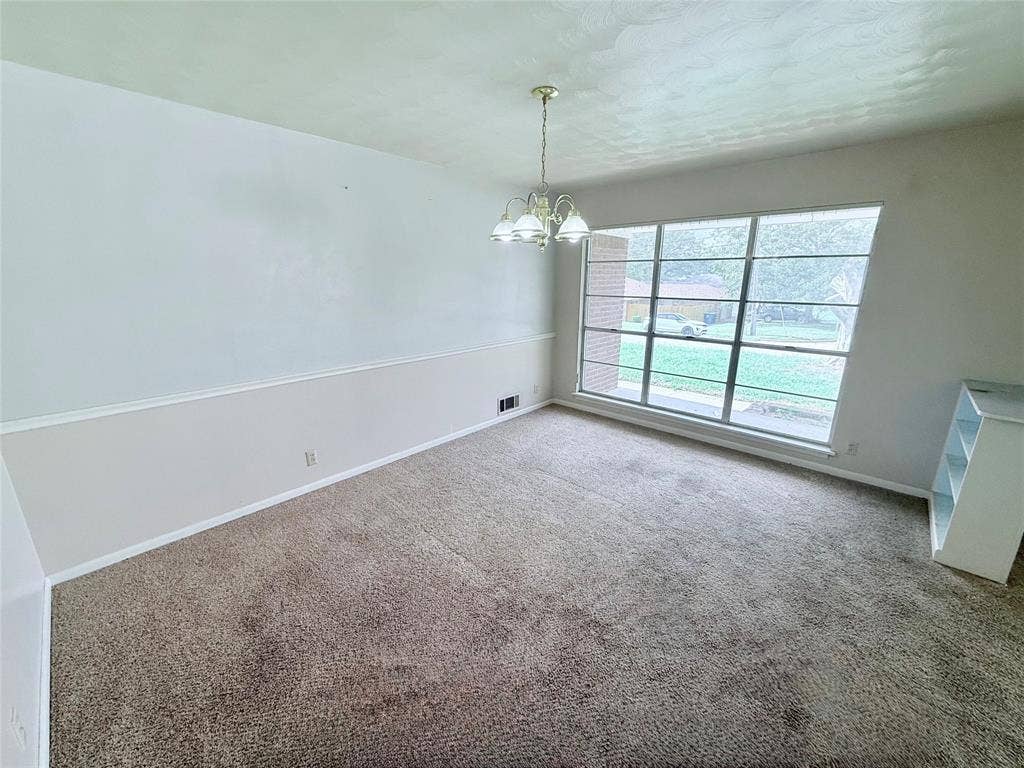 1500 S Houston, Denison, TX 75020 Interior space featuring neutral wall-to-wall carpeting, chair rail molding, a large multi-pane window, and a multi-arm chandelier