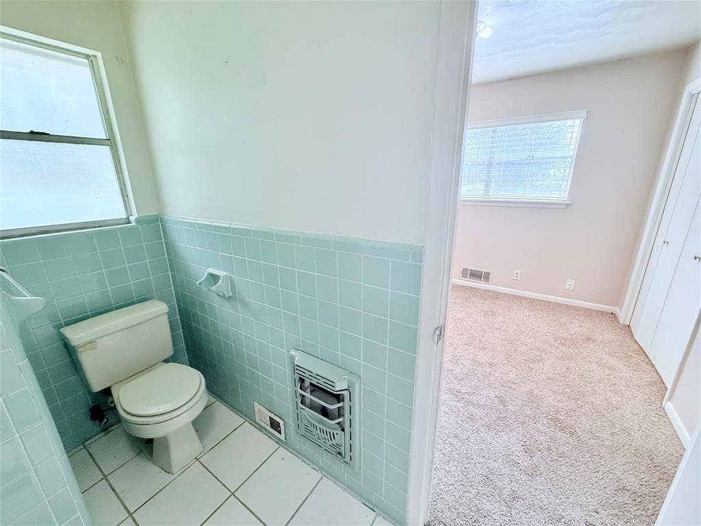 1500 S Houston, Denison, TX 75020 Bathroom featuring light blue wall tiles, white floor tile, a porcelain toilet, and a built-in wall heater