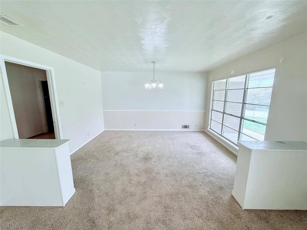 1500 S Houston, Denison, TX 75020 Large room featuring carpeted flooring, white wainscoting, a multi-light chandelier, and a substantial window pane assembly