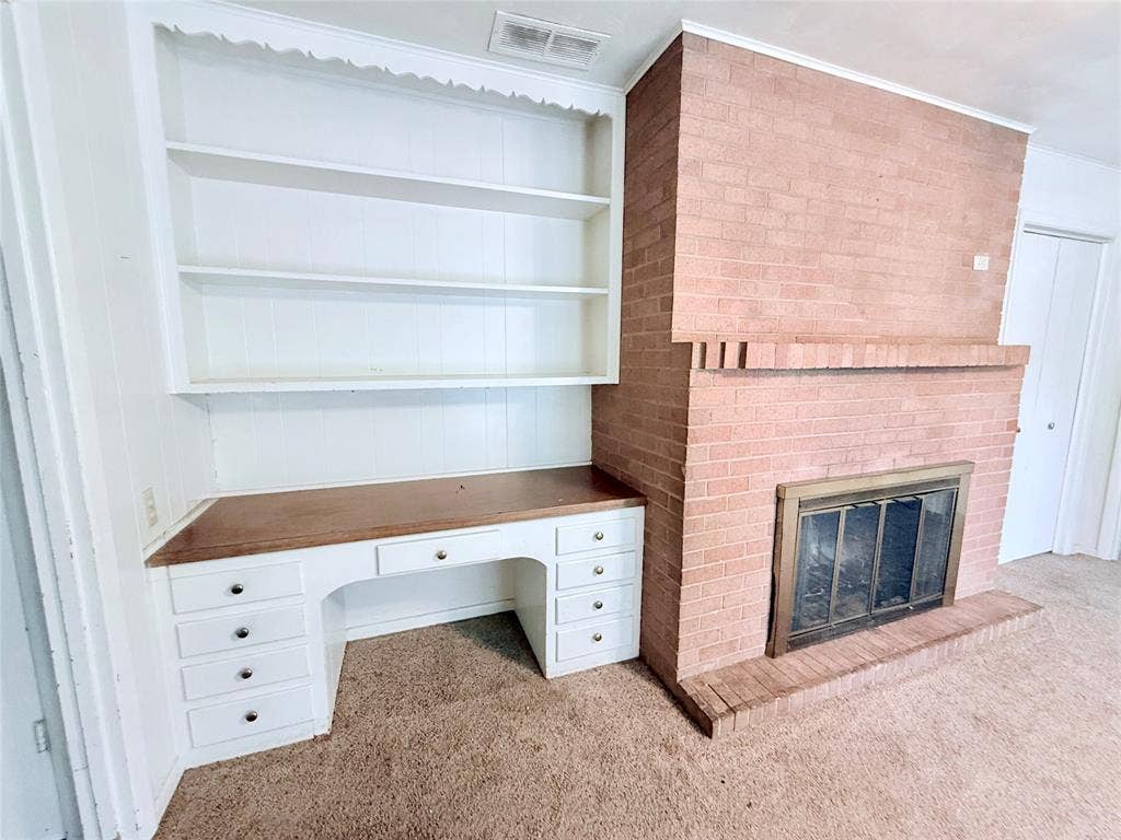 1500 S Houston, Denison, TX 75020 Brick fireplace surround with a raised hearth, metal fireplace screen, and integrated white built-in desk with multiple drawers and open shelving