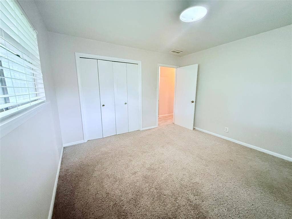 1500 S Houston, Denison, TX 75020 Neutral wall color, carpeted flooring, bi-fold closet doors, and horizontal slat window blinds