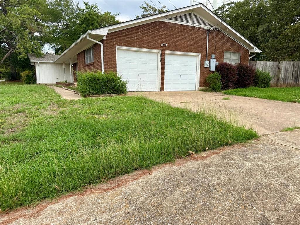 1500 S Houston, Denison, TX 75020 Brick exterior featuring a dual-bay garage, concrete driveway, and gabled roofline