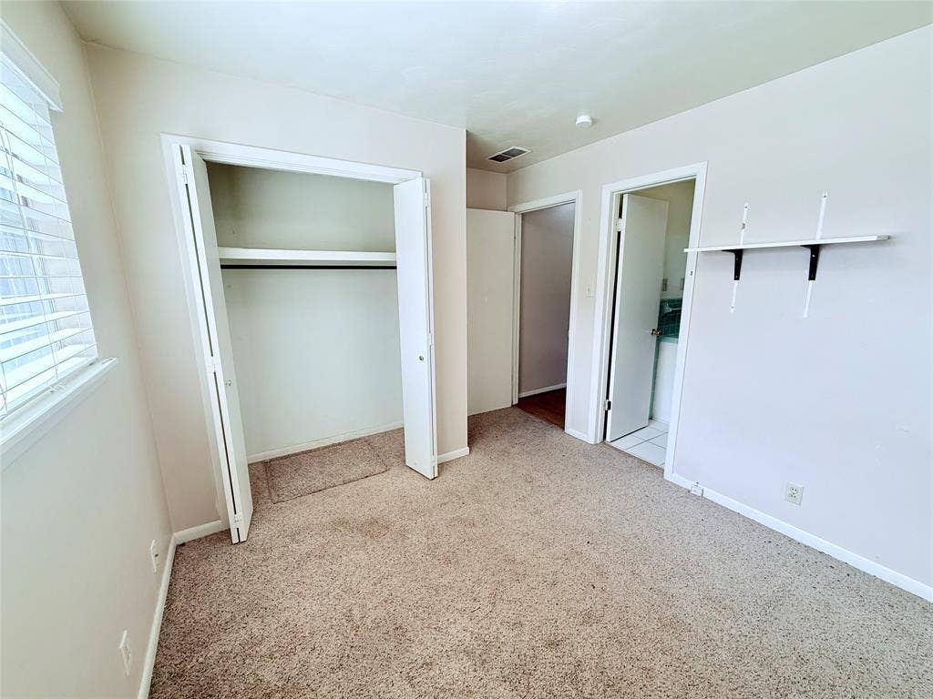1500 S Houston, Denison, TX 75020 Neutral wall-to-wall carpeting, closet with built-in shelving, white-finished interior doors, and wall-mounted shelving unit