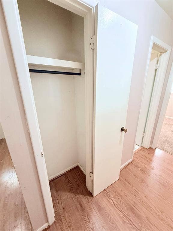 1500 S Houston, Denison, TX 75020 Storage closet featuring white-finish interior shelving, a metal rod, and a white swing door with a metallic knob, complemented by wood-finish flooring