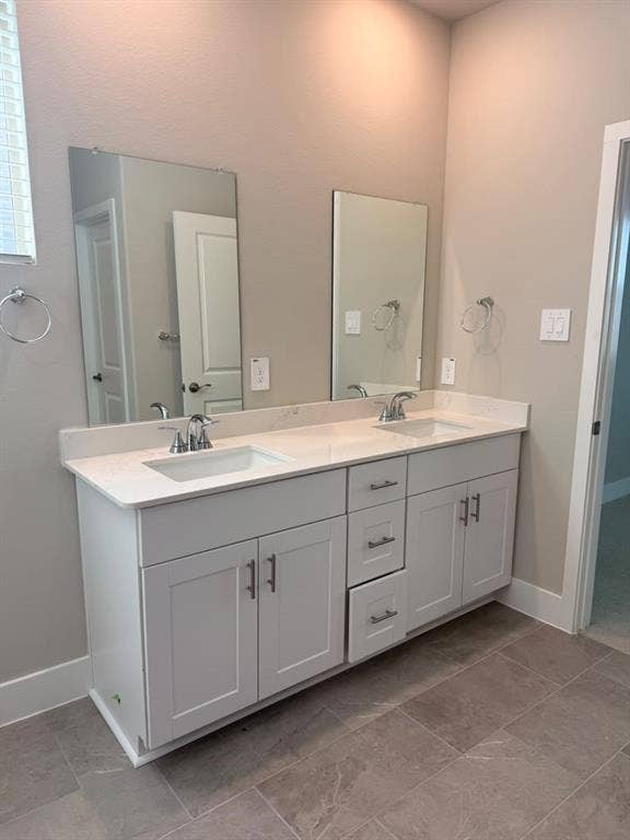 1313 Winters Way, Princeton, TX 75071 Double-sink vanity featuring white shaker-style cabinetry, stone-composite countertop with integrated rectangular basins, polished chrome fixtures, and dual frameless mirrors