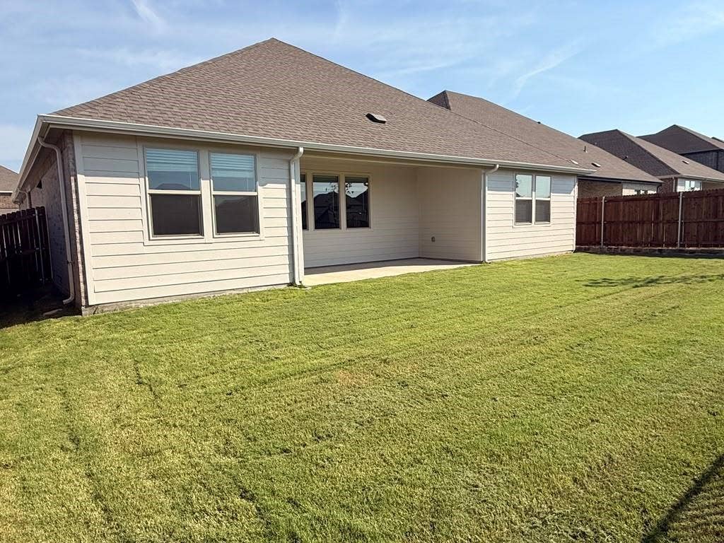 1313 Winters Way, Princeton, TX 75071 Rear exterior featuring horizontal lap siding, a covered concrete patio, multi-pane windows, asphalt shingle roofing, and a privacy-fenced backyard