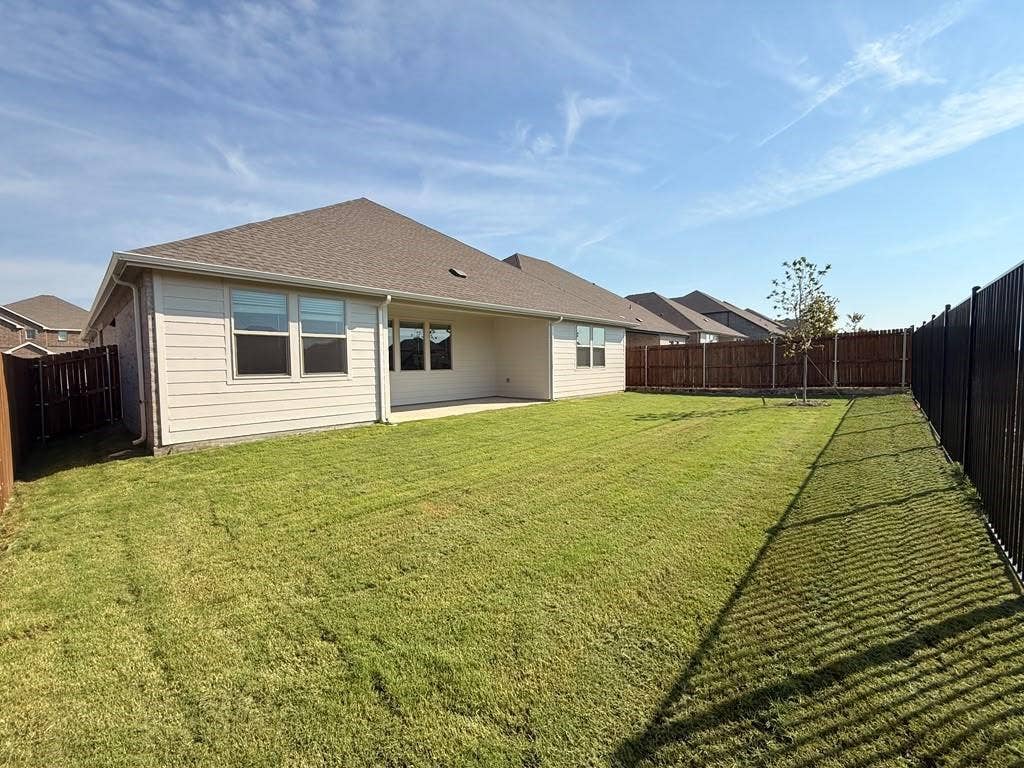 1313 Winters Way, Princeton, TX 75071 Rear exterior featuring a covered patio, horizontal siding, and a fenced-in lawn area