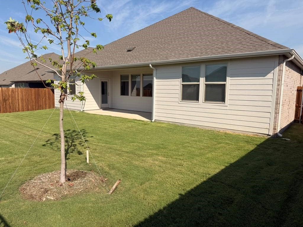 1313 Winters Way, Princeton, TX 75071 Rear exterior featuring horizontal lap siding, a concrete patio, a shingled roof, and a fenced backyard with a lawn