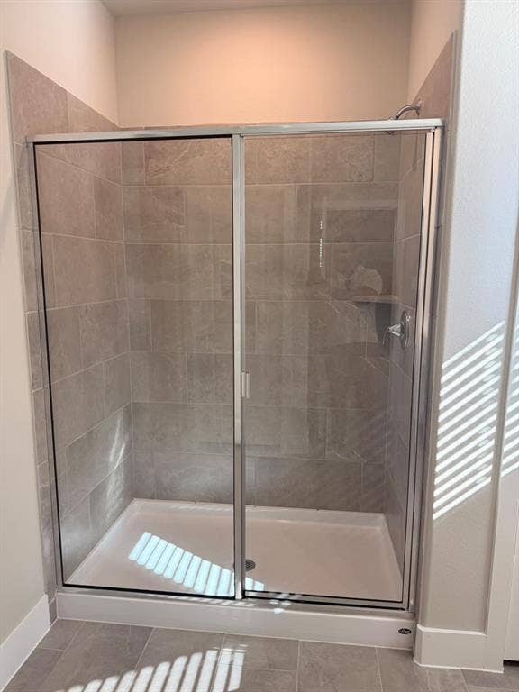 1313 Winters Way, Princeton, TX 75071 Walk-in shower featuring a chrome-framed glass sliding door, neutral-toned tile surround, and a low-profile white shower base