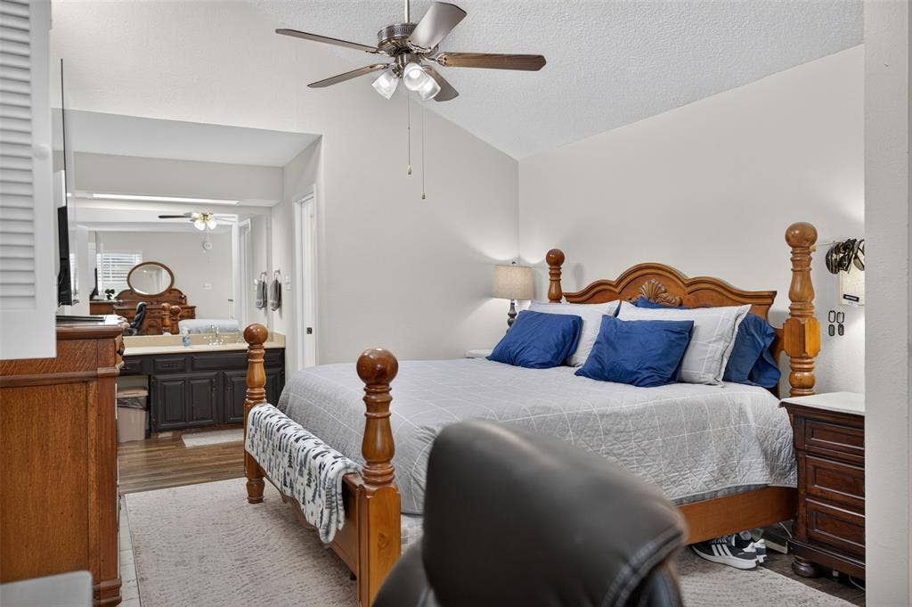 2851 Ursa Circle, Garland, TX 75044 Vaulted ceiling featuring a ceiling fan with light kit, and a vanity area equipped with dark-finish cabinetry