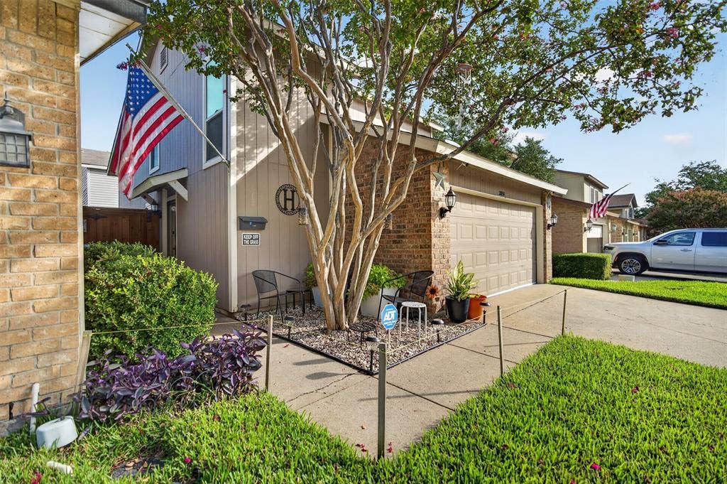 2851 Ursa Circle, Garland, TX 75044 Multi-textured exterior featuring a combination of brick and vertical panel siding, an attached two-car garage, concrete driveway, and mature landscaping