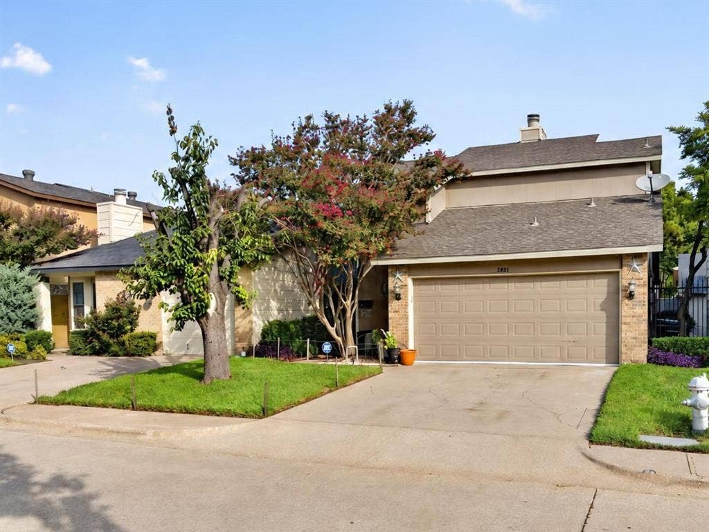 2851 Ursa Circle, Garland, TX 75044 Two-car garage featuring a concrete floor, overhead sectional door, and built-in wall shelving