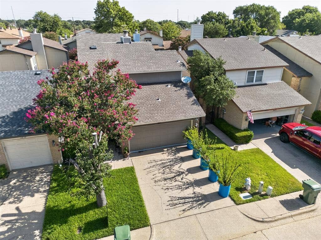 2851 Ursa Circle, Garland, TX 75044 Aerial view featuring a multi-pitched composition shingle roof, central masonry chimney, and landscaped grounds with mature trees