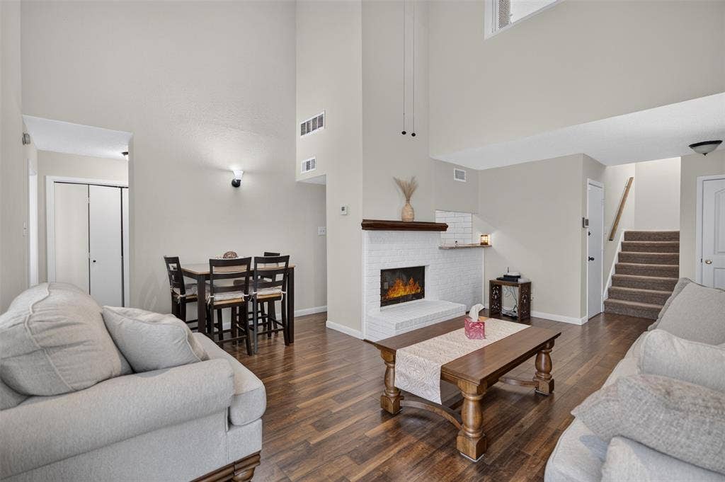 2851 Ursa Circle, Garland, TX 75044 Vaulted ceilings, wood-finish flooring, white painted brick fireplace with a wood mantel, ceiling fan, and sliding glass door leading to an outdoor space