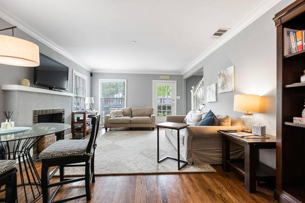 Living area featuring wood-finish flooring, crown molding, and a fireplace with a masonry hearth