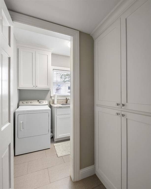 Utility space featuring white shaker-style cabinetry, floor-to-ceiling built-in storage, stone-surfaced countertop with undermount sink, and tile flooring