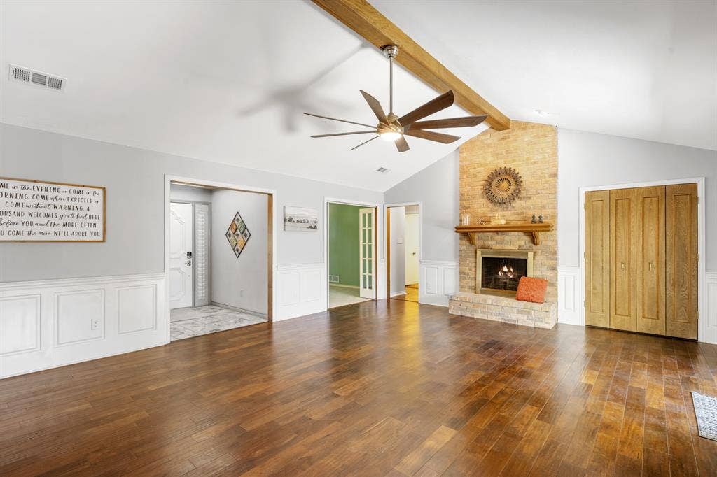 2510 Buttercup Drive, Richardson, TX 75082 Spacious living room featuring rich wood flooring, and a striking floor-to-ceiling brick fireplace with wood mantel.