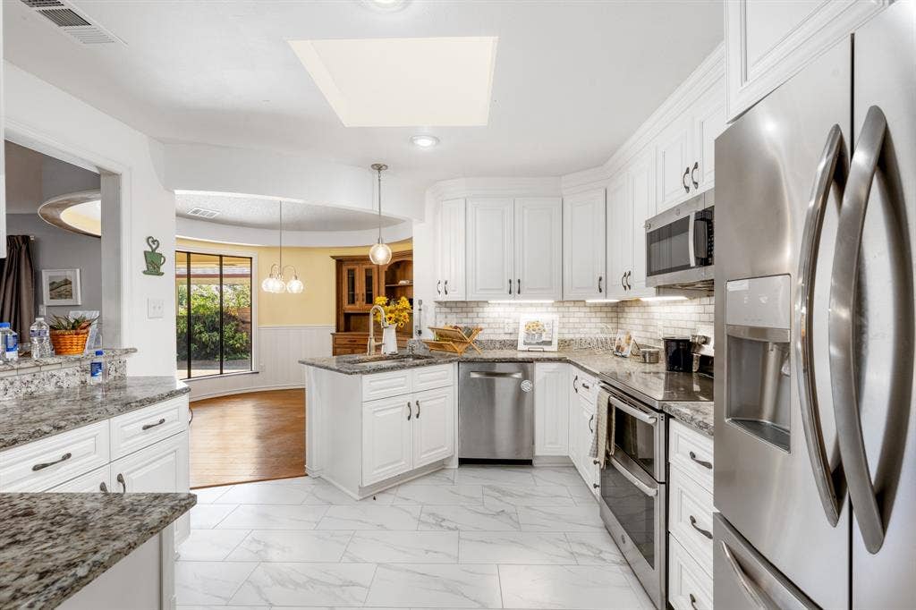2510 Buttercup Drive, Richardson, TX 75082 Beautifully updated kitchen featuring crisp white cabinetry, granite countertops, stainless steel appliances, and a stylish subway-tile backsplash. The generous layout offers abundant storage, and a seamless connection to the bright dining area.