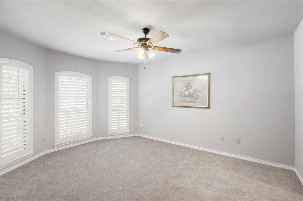 2510 Buttercup Drive, Richardson, TX 75082 Spacious secondary bedroom featuring plush carpeting, soft neutral tones, and an abundance of natural light through three beautifully framed windows with plantation shutters. The generous layout offers plenty of room for comfortable furnishings and a relaxing retreat.