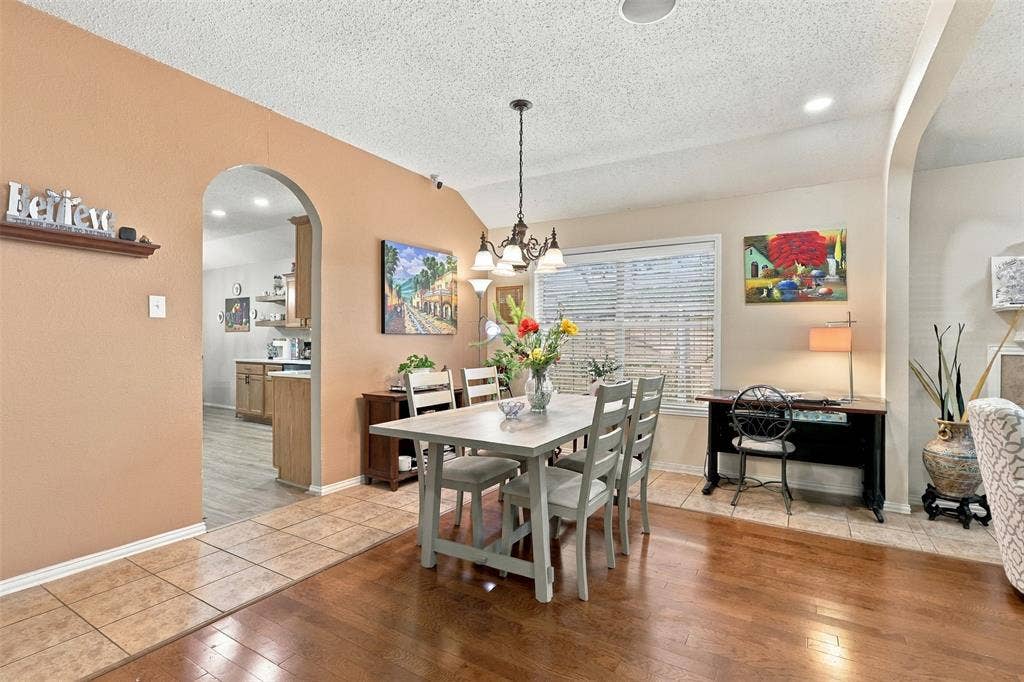 873 Hope Lane, Irving, TX 75061 Dining area featuring wood-finish flooring, ceramic tile flooring, a multi-light chandelier, and arched wall openings