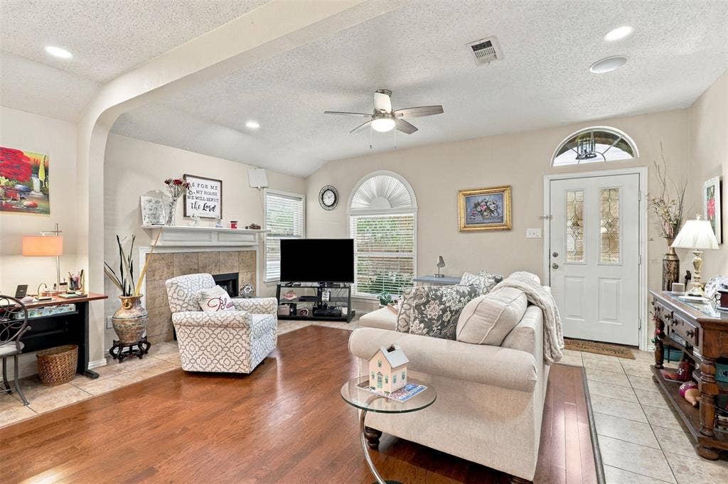 873 Hope Lane, Irving, TX 75061 Living area featuring wood-finish flooring, a fireplace with tile surround, an arched entryway, recessed lighting, and a ceiling fan