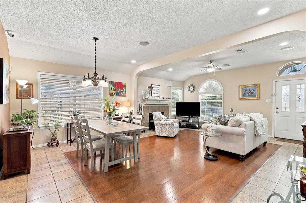 873 Hope Lane, Irving, TX 75061 Open floor plan featuring wood-finish flooring, a fireplace with a stone-surround mantel, arched architectural detailing, and custom windows including a decorative transom
