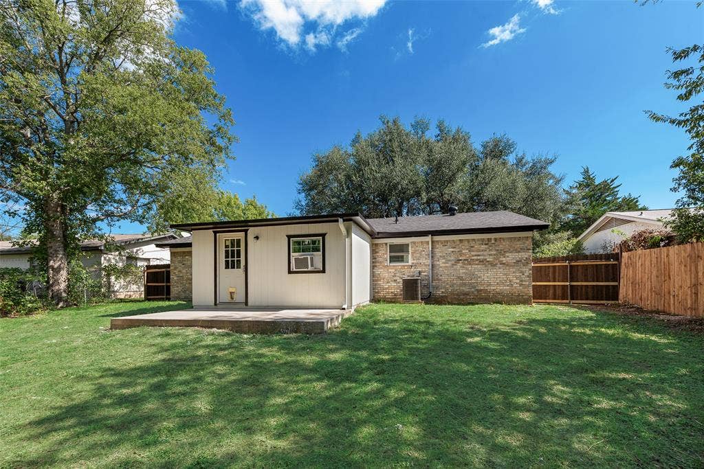 1238 Neptune Drive, Cedar Hill, TX 75104 Rear exterior featuring a concrete patio, brick and vertical siding facade, and enclosed wooden fencing