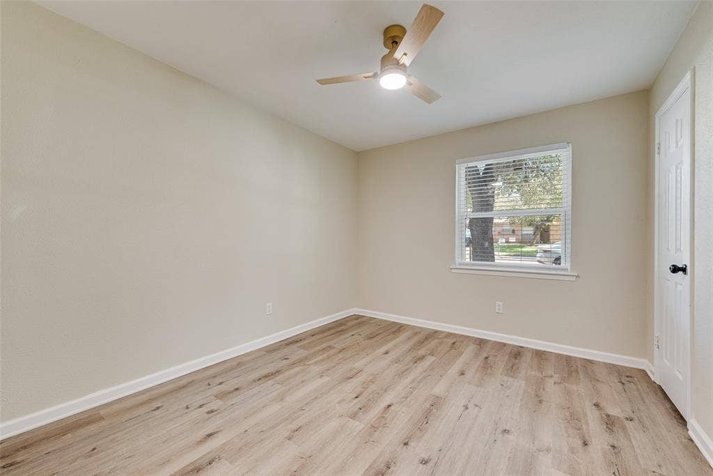 1238 Neptune Drive, Cedar Hill, TX 75104 Neutral-toned walls paired with wood-finish flooring, featuring a central ceiling fan with an integrated light fixture and a single-pane window