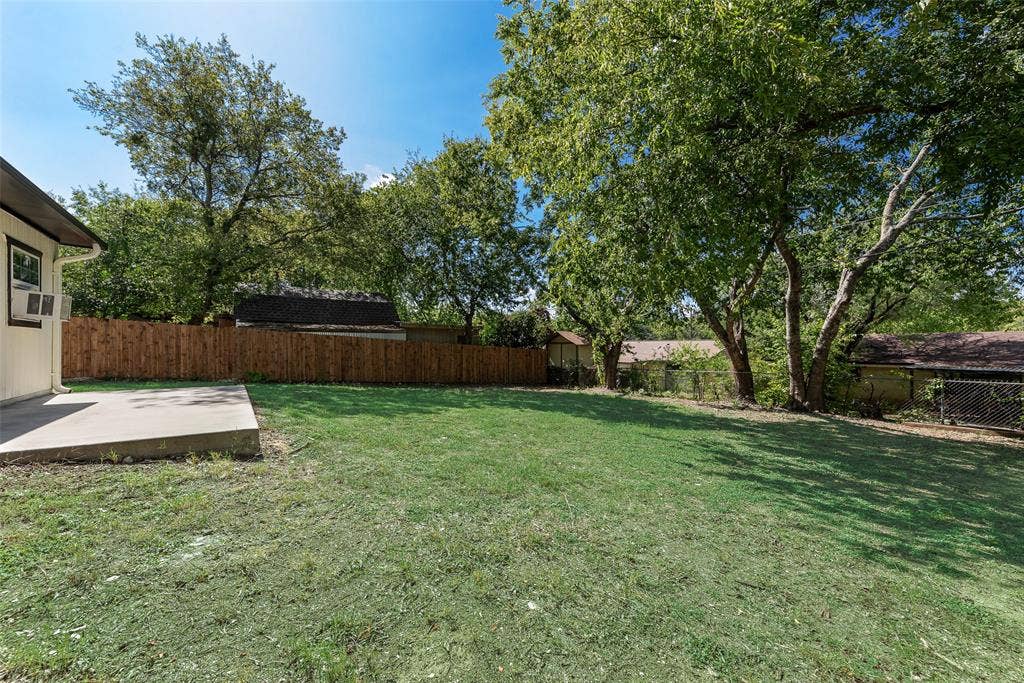 1238 Neptune Drive, Cedar Hill, TX 75104 Backyard featuring a concrete patio, wood privacy fencing, and mature trees