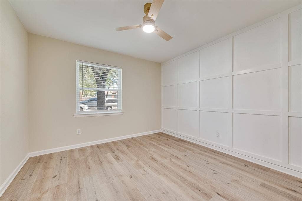 1238 Neptune Drive, Cedar Hill, TX 75104 Room featuring white grid-pattern wall molding, wood-finish flooring, a single-hung window, and a modern ceiling fan with integrated lighting