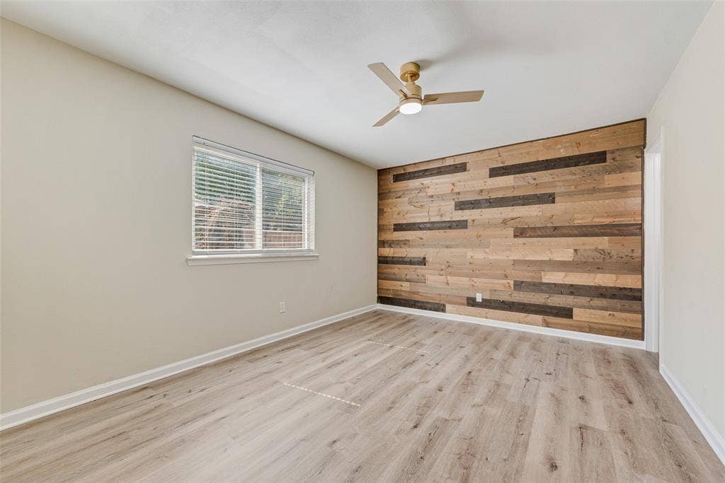 1238 Neptune Drive, Cedar Hill, TX 75104 Wood-plank accent wall, wood-finish flooring, and ceiling fan with integrated lighting