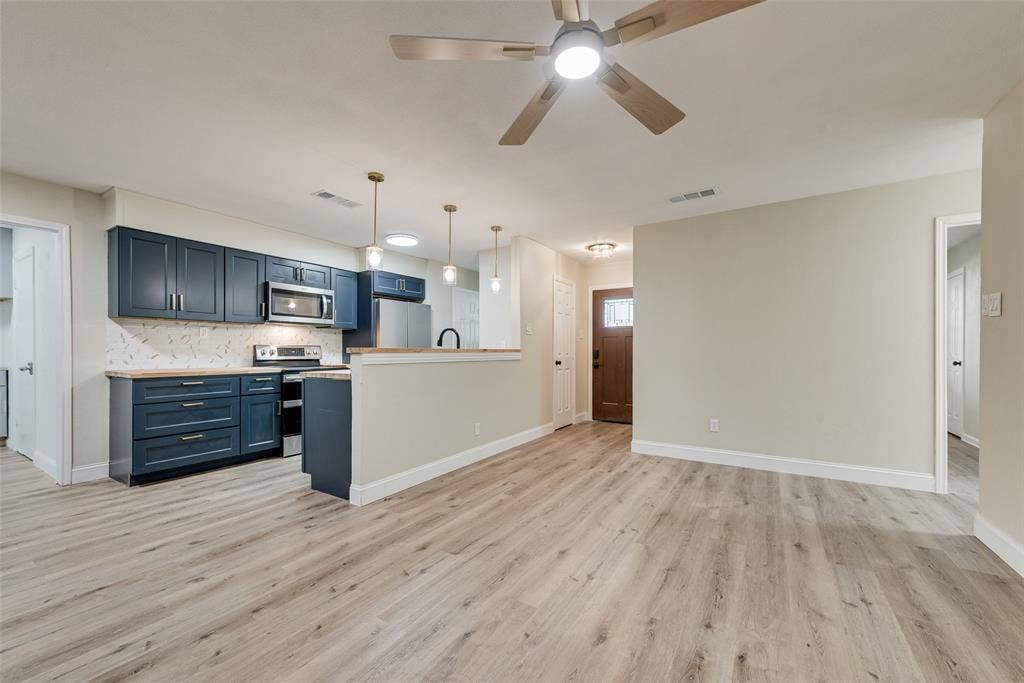 1238 Neptune Drive, Cedar Hill, TX 75104 Kitchen featuring dark blue cabinetry, wood-finish flooring, stone-pattern backsplash, stainless steel appliances, and pendant lighting