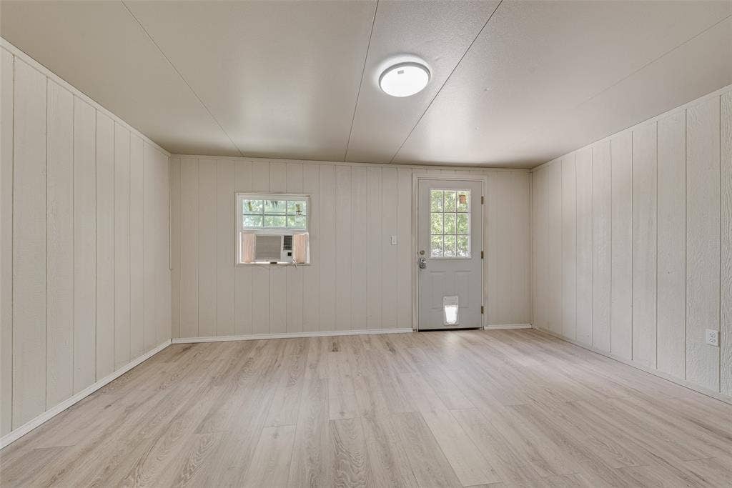 1238 Neptune Drive, Cedar Hill, TX 75104 Interior space featuring neutral vertical paneling, wood-finish flooring, a single-lite exterior door, and a flush-mount ceiling light fixture