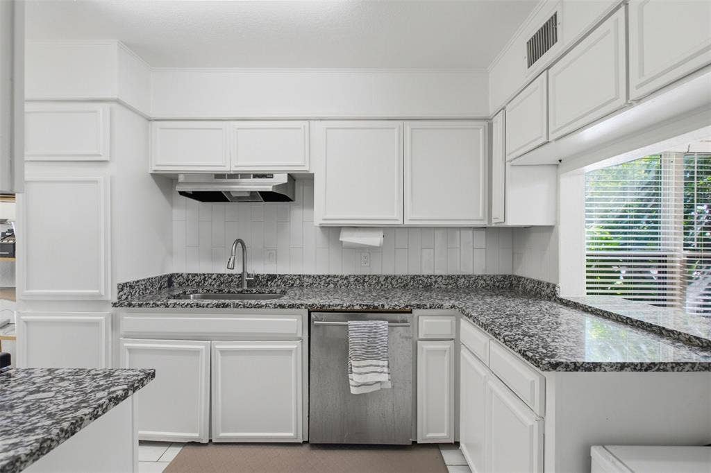 Kitchen featuring white shaker-style cabinetry, stone-finish countertops, stainless steel dishwasher, subway tile backsplash, and a high-arc faucet