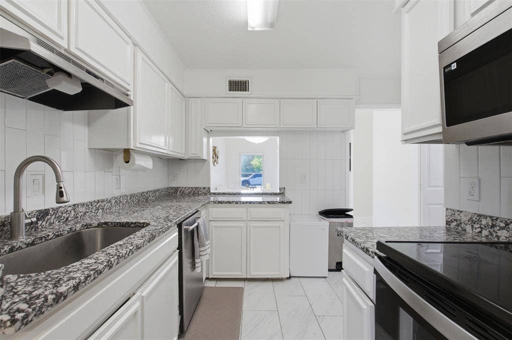 Kitchen featuring white cabinetry, stone-finish countertops, stainless steel appliances, a pull-down kitchen faucet, and tile flooring