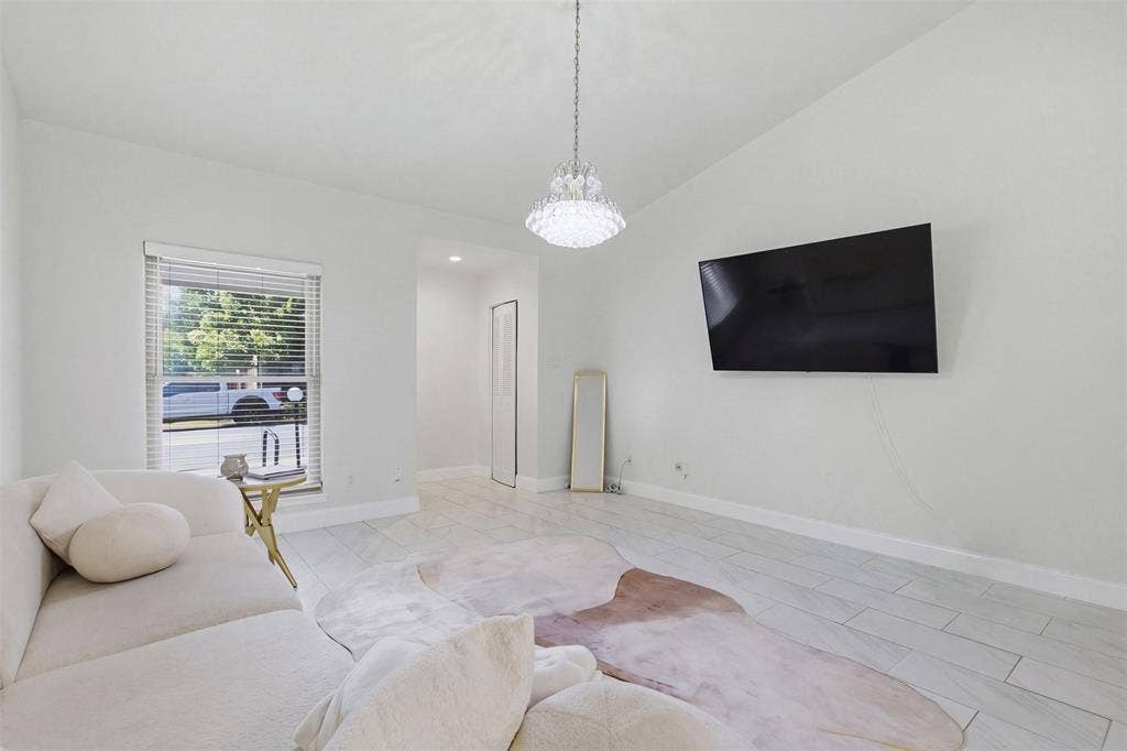 Light-filled interior featuring large-format tile flooring, a multi-tiered crystal chandelier, and neutral wall tones