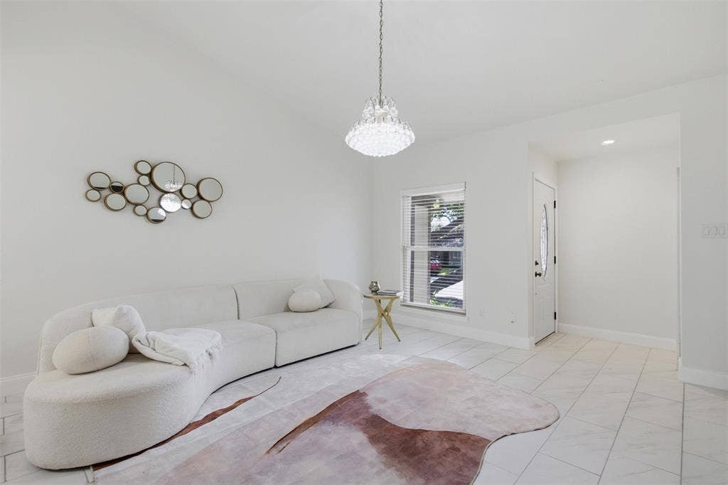 Bright interior space featuring polished tile flooring, a tiered crystal chandelier, and a single-pane window