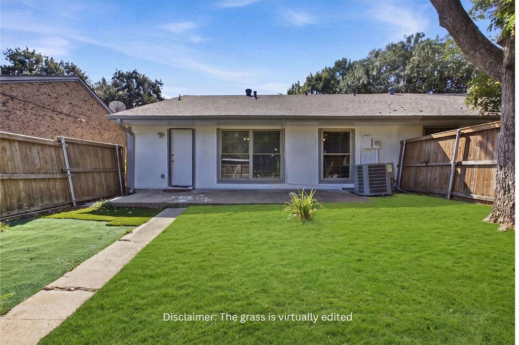 Rear exterior featuring a concrete patio, wood privacy fencing, and mature tree